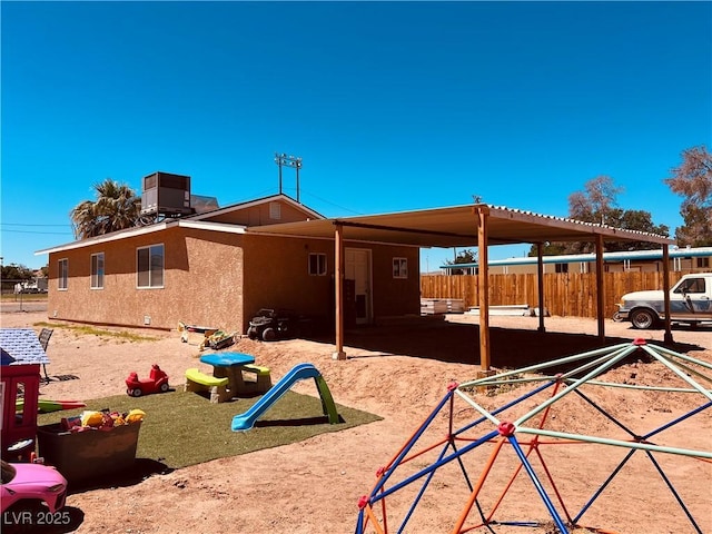 back of house featuring fence, central AC unit, and stucco siding
