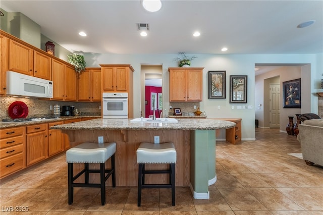 8125 Soledad Canyon St, Las Vegas, NV 89131 - kitchen featuring white appliances, tasteful backsplash, a breakfast bar, a sink, and an island with sink