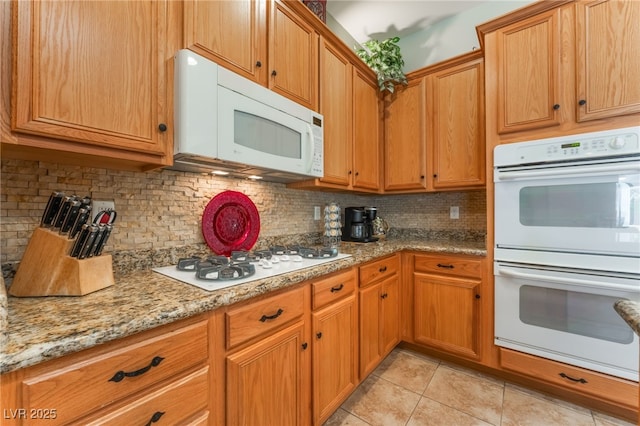 8125 Soledad Canyon St, Las Vegas, NV 89131 - kitchen featuring white appliances, light tile patterned flooring, backsplash, light stone counters, and brown cabinetry