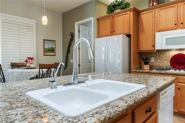 8125 Soledad Canyon St, Las Vegas, NV 89131 - kitchen with white appliances, a sink, brown cabinetry, hanging light fixtures, and backsplash