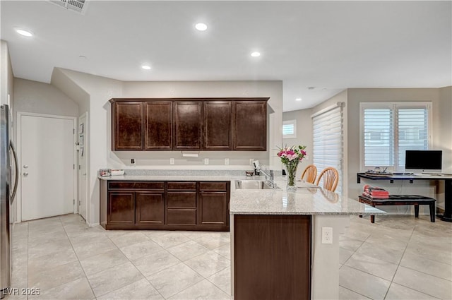 9327 S Chieftain St, Las Vegas, NV 89178 - kitchen featuring a sink, a peninsula, dark brown cabinets, light tile patterned floors, and recessed lighting