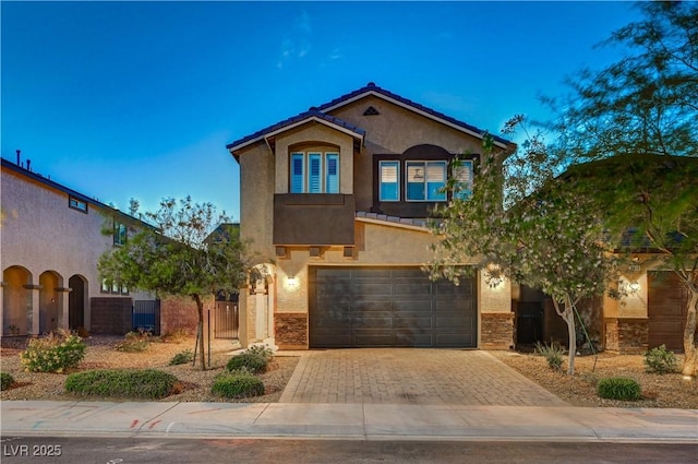 9327 S Chieftain St, Las Vegas, NV 89178 - mediterranean / spanish-style house featuring stucco siding, decorative driveway, an attached garage, stone siding, and fence
