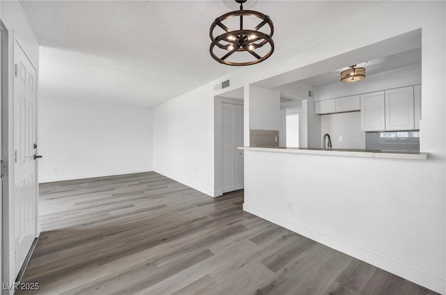 1424 Santa Anita Dr Unit D, Las Vegas, NV 89119 - kitchen with a chandelier, wood finished floors, baseboards, a peninsula, and a sink