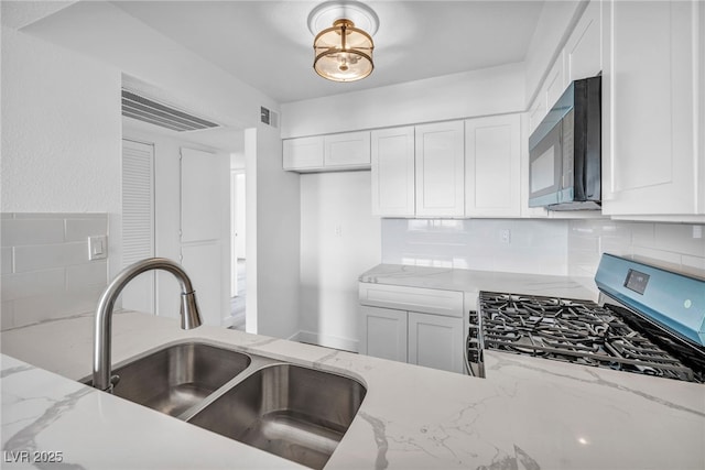 1424 Santa Anita Dr Unit D, Las Vegas, NV 89119 - kitchen featuring black microwave, a sink, decorative backsplash, white cabinets, and stainless steel gas range oven