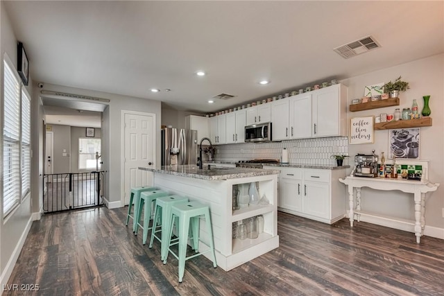 680 Moonlight Stroll St, Henderson, NV 89002 - kitchen with open shelves, appliances with stainless steel finishes, dark wood-style flooring, light stone countertops, and white cabinets