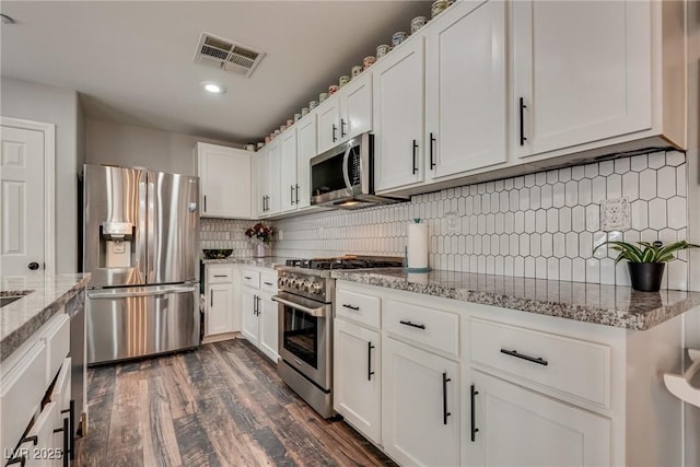 680 Moonlight Stroll St, Henderson, NV 89002 - kitchen featuring appliances with stainless steel finishes, decorative backsplash, white cabinets, dark wood-style floors, and light stone countertops