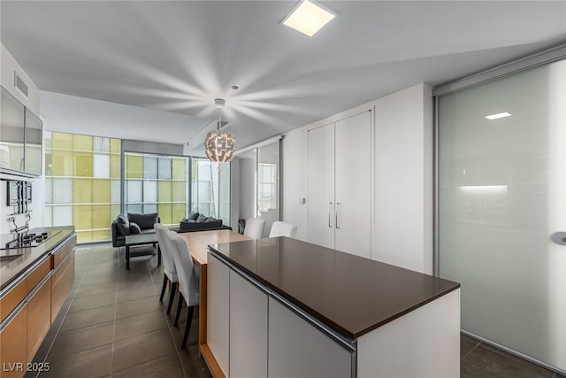 kitchen featuring dark tile patterned floors, dark countertops, a kitchen island, and a chandelier
