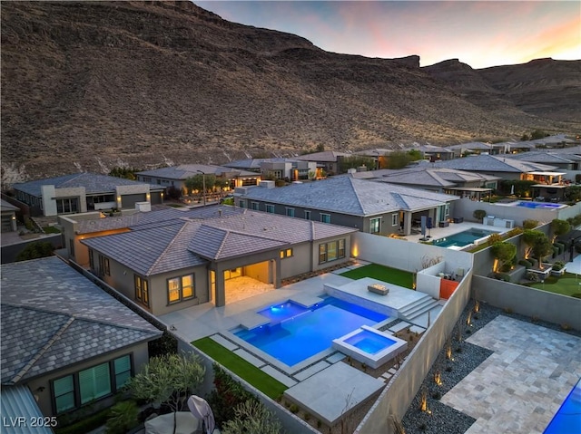 10048 Copper Edge Rd, Las Vegas, NV 89148 - pool at dusk featuring a residential view, a fenced backyard, a mountain view, and a patio