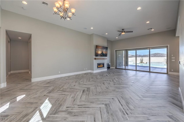 10048 Copper Edge Rd, Las Vegas, NV 89148 - unfurnished living room with a chandelier, a glass covered fireplace, ceiling fan, recessed lighting, and a towering ceiling