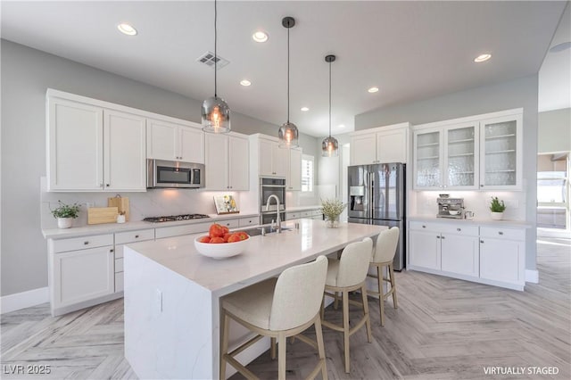 10048 Copper Edge Rd, Las Vegas, NV 89148 - kitchen with appliances with stainless steel finishes, white cabinets, recessed lighting, a kitchen bar, and a kitchen island with sink