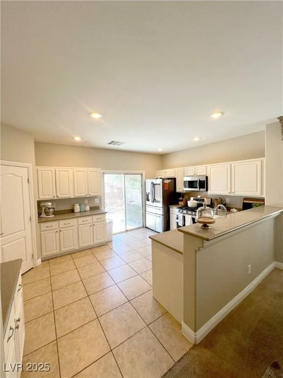 8340 Winterchase Pl, Las Vegas, NV 89143 - kitchen with stainless steel appliances, a peninsula, white cabinets, recessed lighting, and light tile patterned flooring