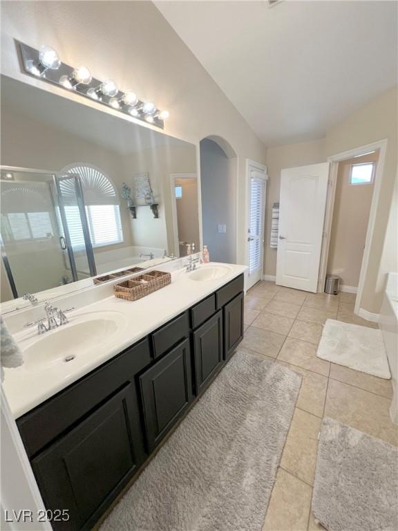 8340 Winterchase Pl, Las Vegas, NV 89143 - bathroom featuring a bath, double vanity, tile patterned flooring, a shower stall, and lofted ceiling