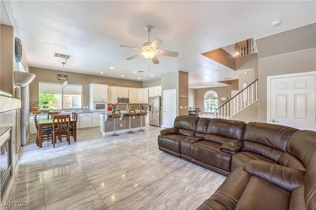 5862 Bluthe Bridge Ave, Las Vegas, NV 89141 - living room featuring ceiling fan, healthy amount of natural light, stairway, and a tiled fireplace