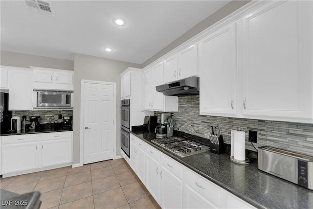11244 Gammila Dr, Las Vegas, NV 89141 - kitchen with under cabinet range hood, stainless steel appliances, backsplash, white cabinets, and light tile patterned floors