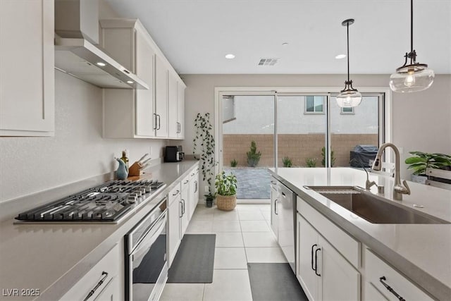 10324 Stroma Ave, Las Vegas, NV 89166 - kitchen featuring stainless steel appliances, wall chimney range hood, a sink, hanging light fixtures, and white cabinets