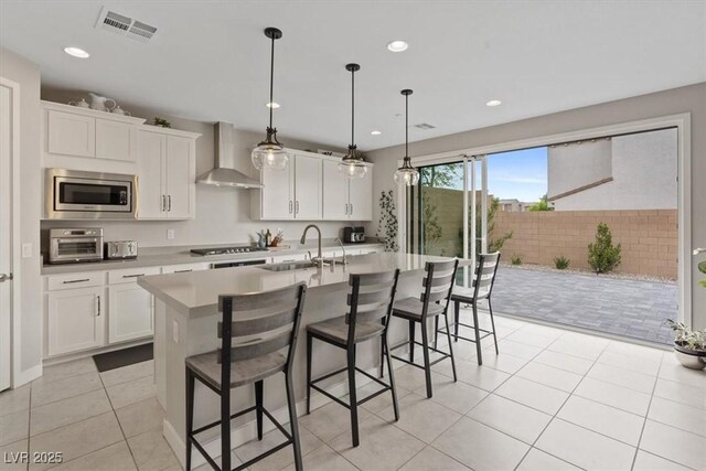 10324 Stroma Ave, Las Vegas, NV 89166 - kitchen featuring wall chimney exhaust hood, stainless steel microwave, light countertops, white cabinets, and a kitchen breakfast bar