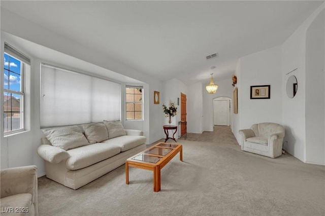 carpeted living room featuring plenty of natural light, arched walkways, and vaulted ceiling