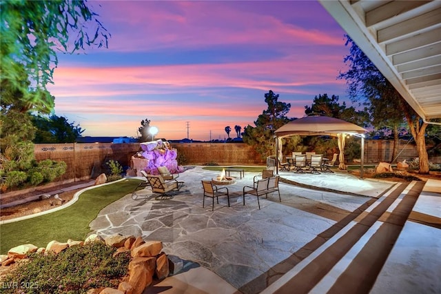 view of patio / terrace with a gazebo, outdoor dining area, a fenced backyard, and a fire pit