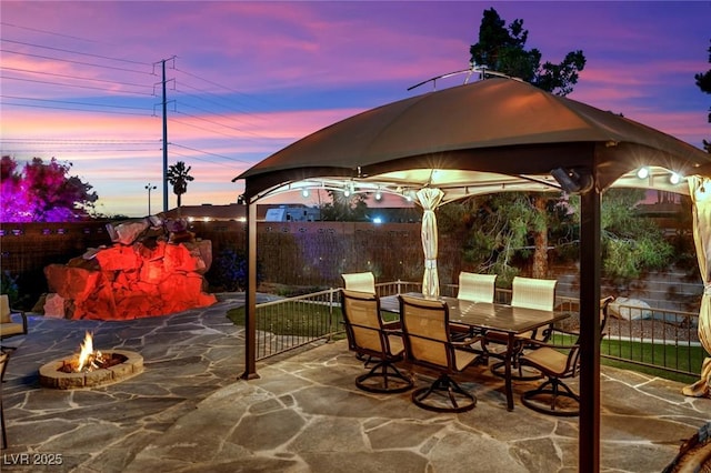 view of patio / terrace with a fire pit, fence, and outdoor dining space