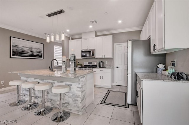 1637 Harvest Pecan Ct, Las Vegas, NV 89108 - kitchen with appliances with stainless steel finishes, light tile patterned flooring, white cabinetry, a center island with sink, and crown molding