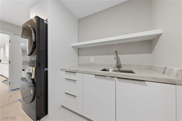 3075 Santa Margarita St, Las Vegas, NV 89146 - kitchen with stacked washer / drying machine, a sink, modern cabinets, white cabinetry, and light countertops