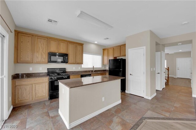125 Sharp Edge Ave, North Las Vegas, NV 89031 - kitchen featuring black appliances, a sink, dark stone counters, a kitchen island, and baseboards