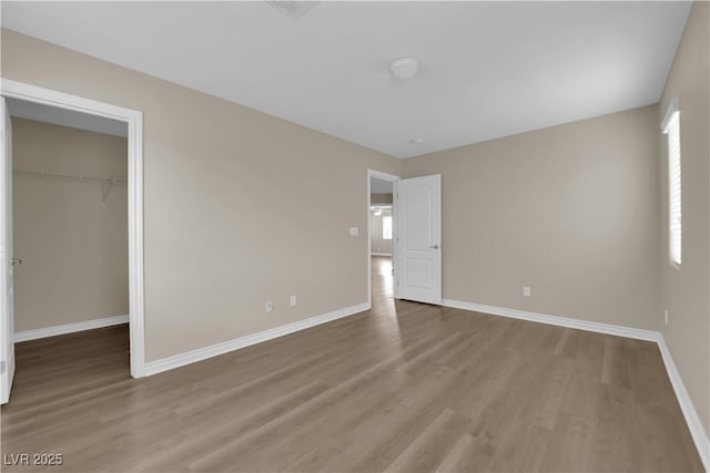 125 Sharp Edge Ave, North Las Vegas, NV 89031 - unfurnished bedroom with wood finished floors, baseboards, a spacious closet, and a closet