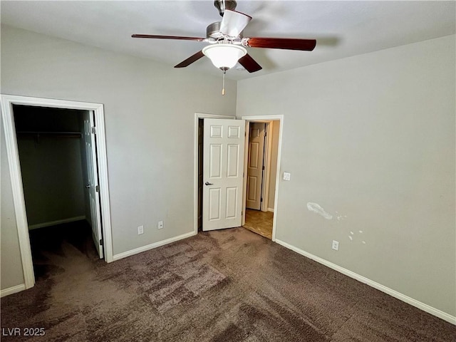 unfurnished bedroom with carpet, a spacious closet, baseboards, a closet, and a ceiling fan