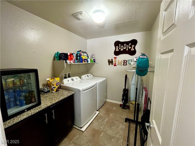washroom featuring washer and dryer, tile patterned floors, cabinet space, a textured ceiling, and baseboards
