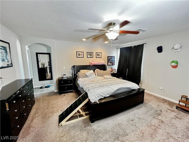 carpeted bedroom featuring arched walkways, a ceiling fan, and baseboards