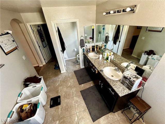 full bath featuring toilet, tile patterned floors, and double vanity