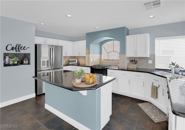 10902 Fintry Hills St, Las Vegas, NV 89141 - kitchen with stainless steel fridge, black gas range oven, a sink, white cabinetry, and tasteful backsplash