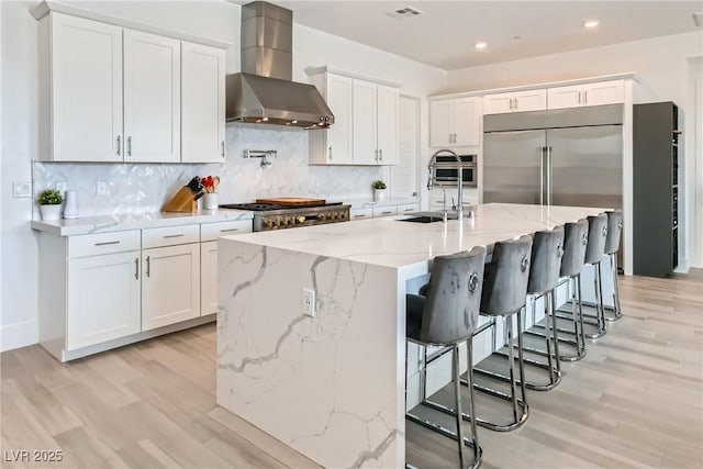 5321 Brayden Ct, Las Vegas, NV 89131 - kitchen featuring wall chimney range hood, stainless steel built in fridge, a sink, light wood-type flooring, and recessed lighting