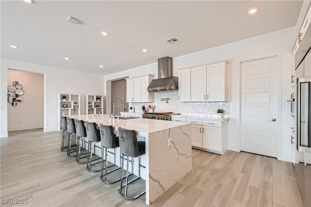 5321 Brayden Ct, Las Vegas, NV 89131 - kitchen with wall chimney exhaust hood, light wood-style floors, decorative backsplash, white cabinetry, and recessed lighting