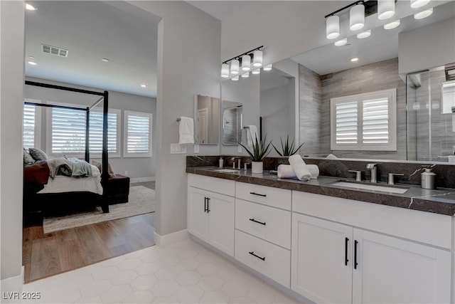 ensuite bathroom featuring tile patterned flooring, a shower with shower door, and double vanity