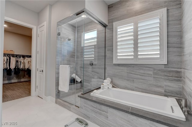 full bathroom featuring a shower stall, a walk in closet, and a bath