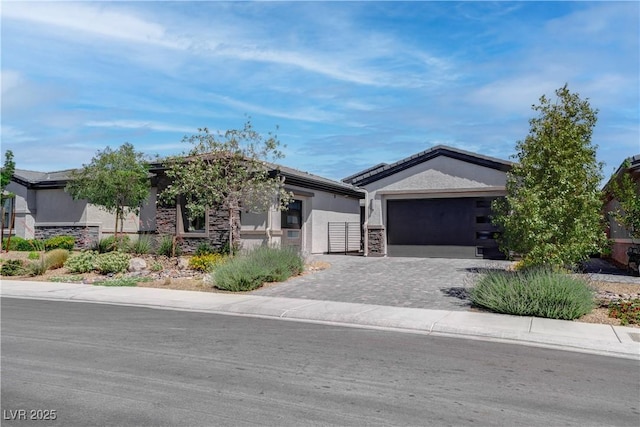 single story home featuring decorative driveway, stucco siding, a garage, and stone siding