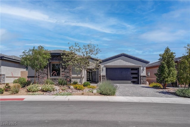 view of front of home featuring decorative driveway, a garage, stone siding, and stucco siding