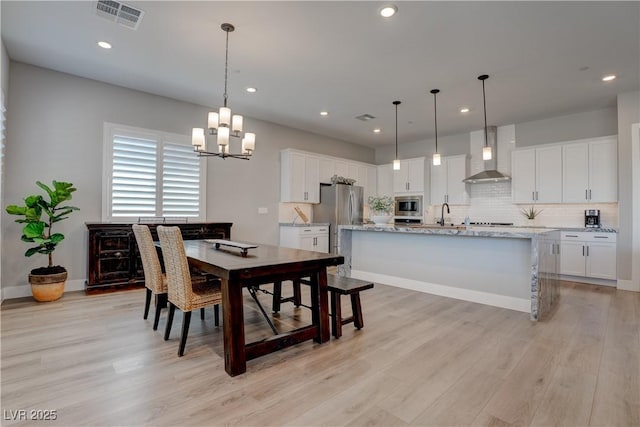 dining room featuring a chandelier, light wood-style flooring, recessed lighting, and baseboards
