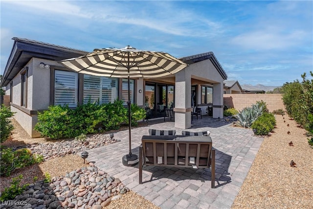 rear view of property featuring stucco siding, a patio area, and fence