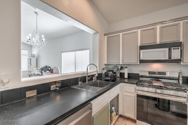 2920 Riarosa Ct, North Las Vegas, NV 89086 - kitchen featuring appliances with stainless steel finishes, a sink, dark countertops, a chandelier, and light tile patterned floors