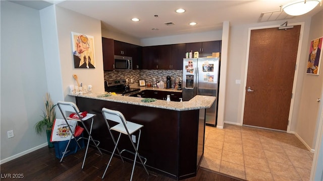 8255 S Las Vegas Blvd Unit 1514, Las Vegas, NV 89123 - kitchen featuring stainless steel appliances, tasteful backsplash, a peninsula, dark brown cabinets, and baseboards