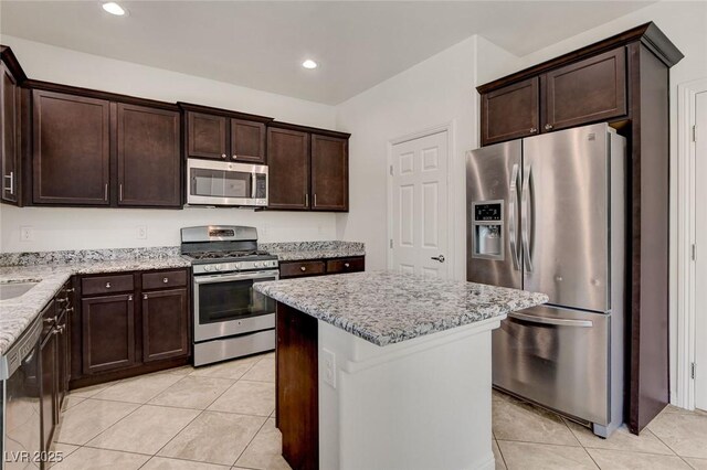 1055 Fish Pond Ave, Henderson, NV 89014 - kitchen with appliances with stainless steel finishes, dark brown cabinets, light stone countertops, light tile patterned flooring, and a center island