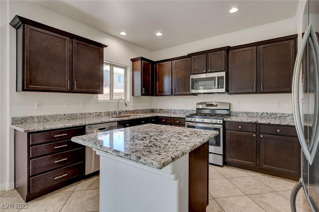 1055 Fish Pond Ave, Henderson, NV 89014 - kitchen featuring stainless steel appliances, a sink, light tile patterned floors, dark brown cabinetry, and a center island