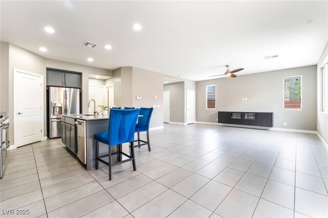 5981 Smith Valley Rd, Las Vegas, NV 89148 - kitchen featuring appliances with stainless steel finishes, a kitchen island with sink, light tile patterned floors, a breakfast bar area, and recessed lighting