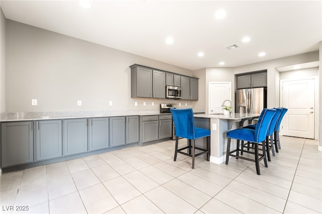 5981 Smith Valley Rd, Las Vegas, NV 89148 - kitchen with stainless steel appliances, gray cabinets, recessed lighting, a kitchen breakfast bar, and light countertops