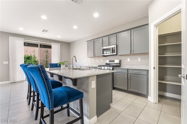 5981 Smith Valley Rd, Las Vegas, NV 89148 - kitchen with appliances with stainless steel finishes, gray cabinetry, a sink, an island with sink, and recessed lighting
