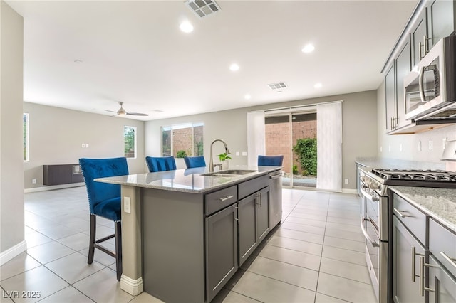 5981 Smith Valley Rd, Las Vegas, NV 89148 - kitchen featuring stainless steel appliances, a sink, gray cabinets, a breakfast bar area, and plenty of natural light