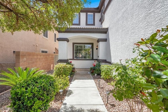 doorway to property featuring stucco siding and fence