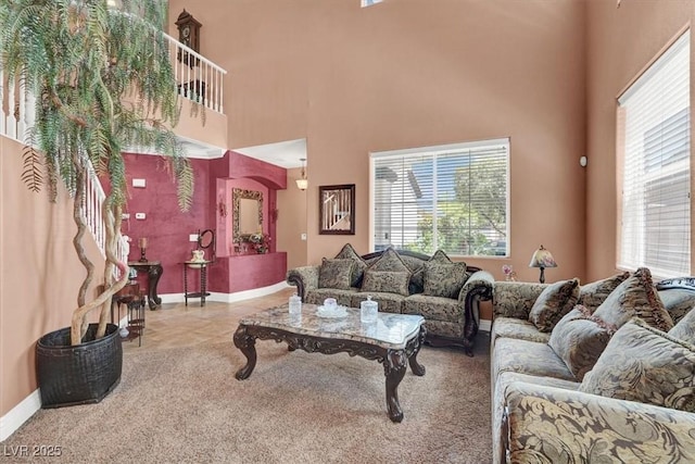 living area with baseboards, a towering ceiling, and carpet flooring